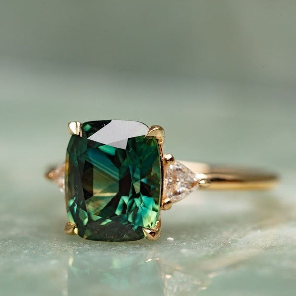 Gold ring with a green gemstone on a light background