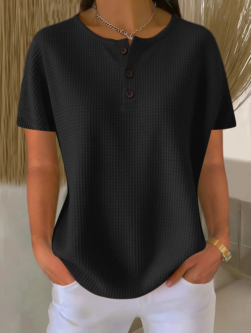 Person wearing a black textured shirt and white pants with a neutral background