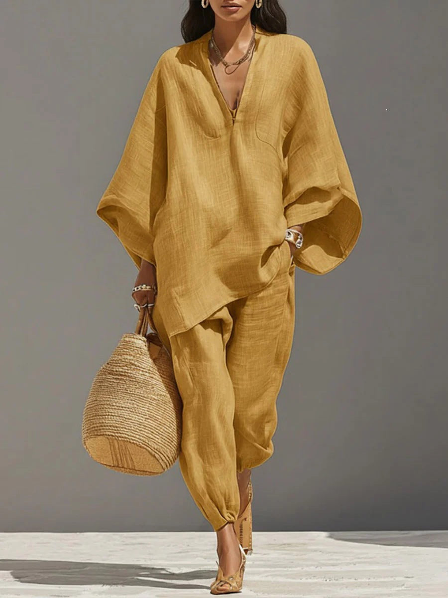 Woman wearing a mustard yellow outfit holding a woven bag on a gray background