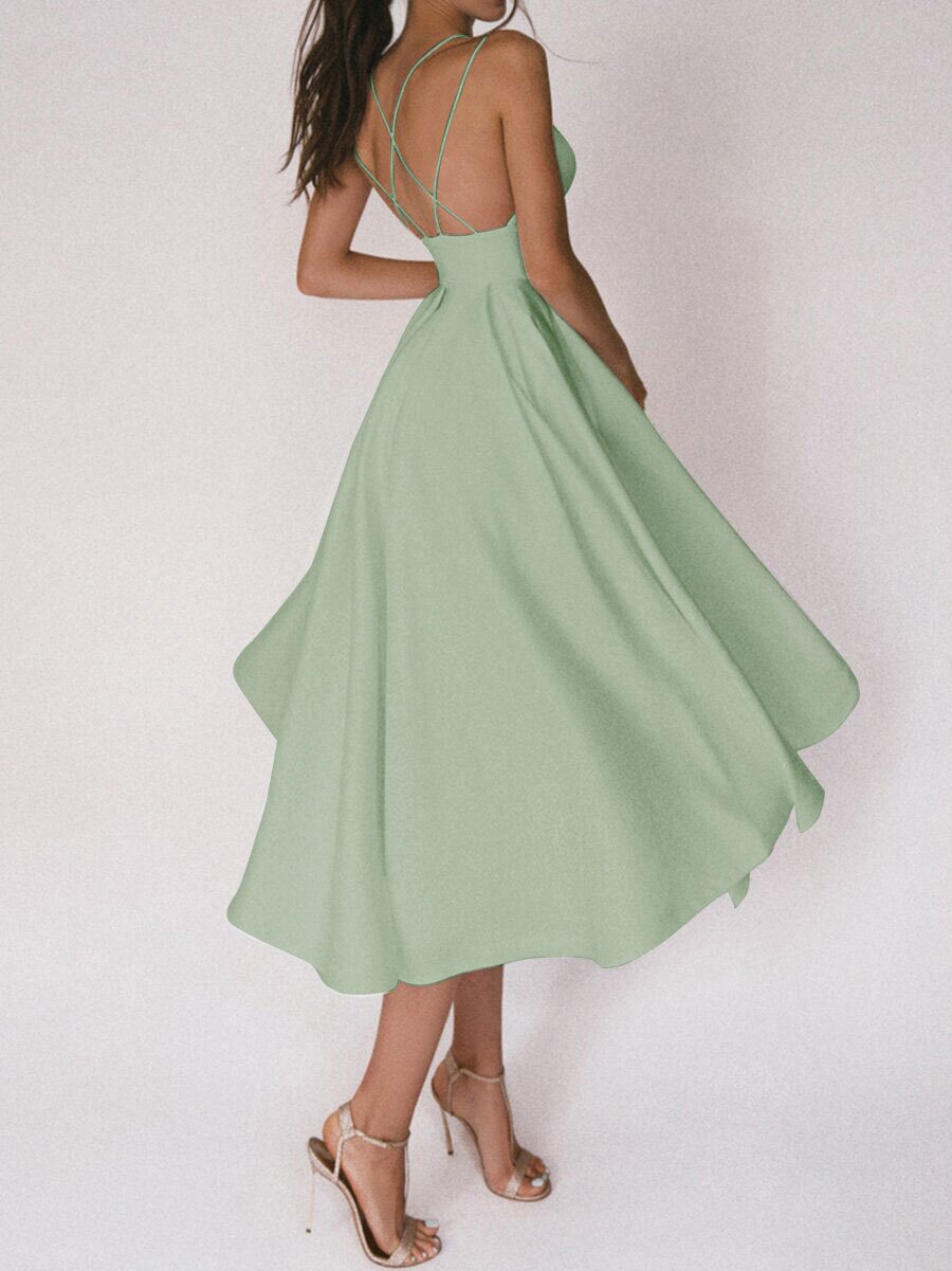 Green dress with thin straps being twirled on a plain background