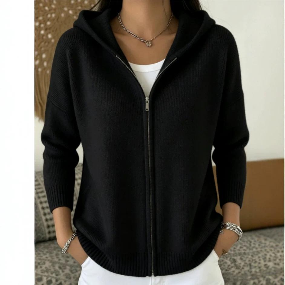 Person wearing a black zip-up hoodie with a neutral background