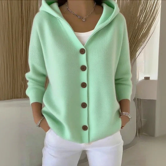 Light green cardigan with brown buttons worn by a person indoors.