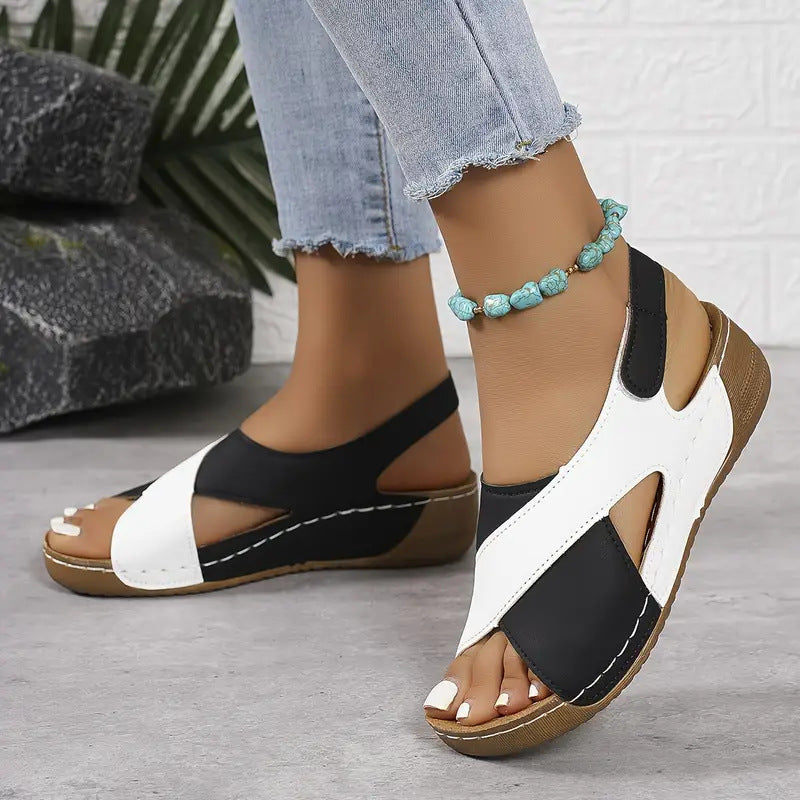 Black and white sandals worn with light blue jeans on a neutral background
