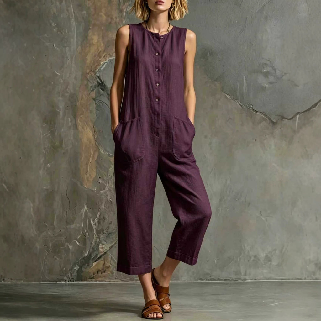 Woman wearing a purple jumpsuit against a textured gray wall.