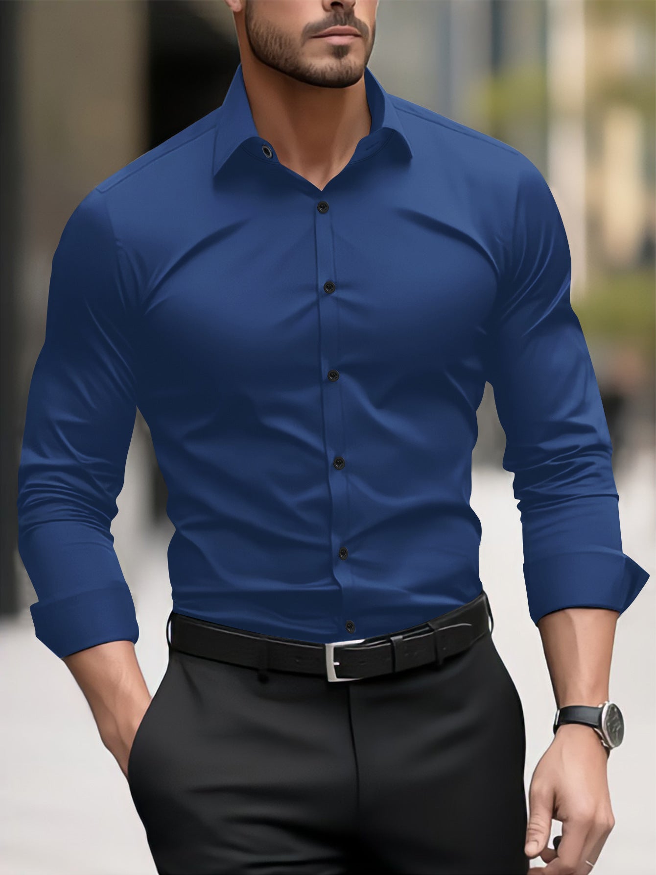 Man wearing a blue dress shirt with rolled-up sleeves and black pants in an urban setting.