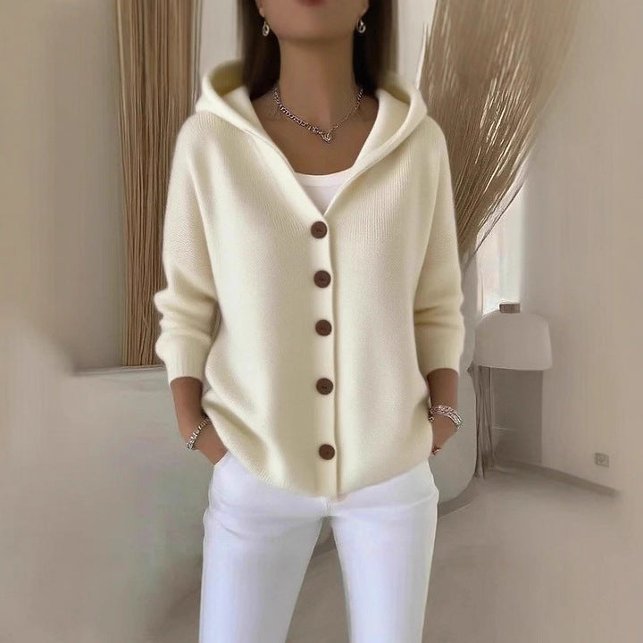 Person wearing a cream-colored cardigan with brown buttons in an indoor setting