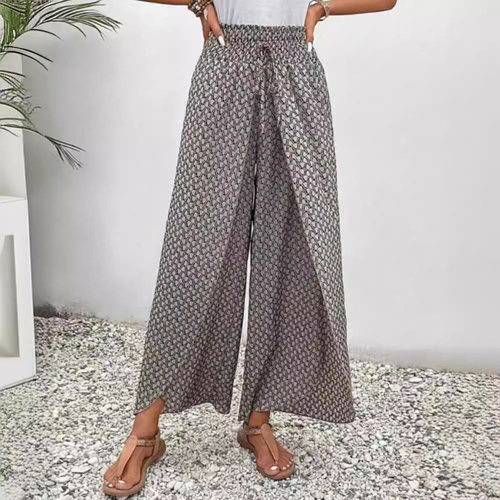 Person wearing floral wide-leg pants on a pebbled surface with a white wall background