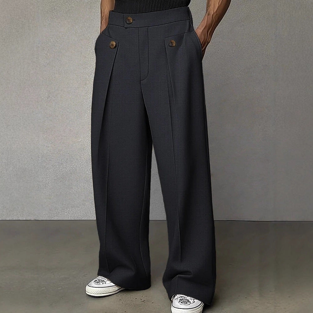 Person wearing dark gray wide-leg pants with brown buttons against a plain background