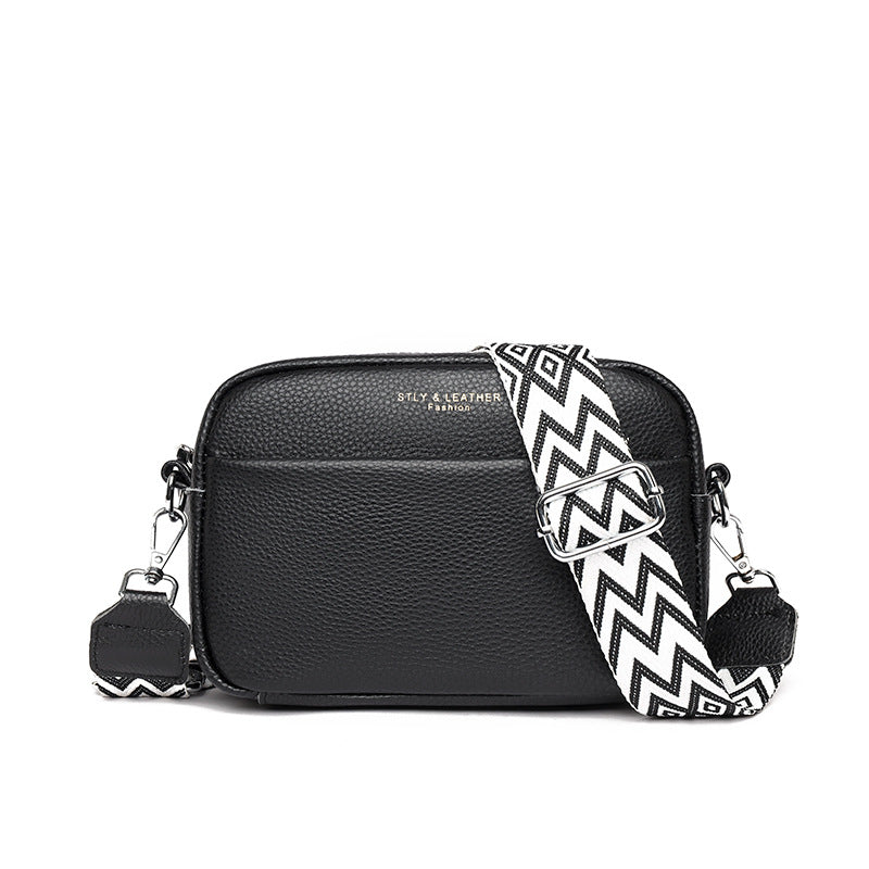 Black crossbody bag with a black and white zigzag strap on a white background