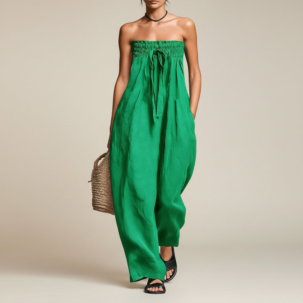 Woman wearing a green strapless jumpsuit against a neutral background