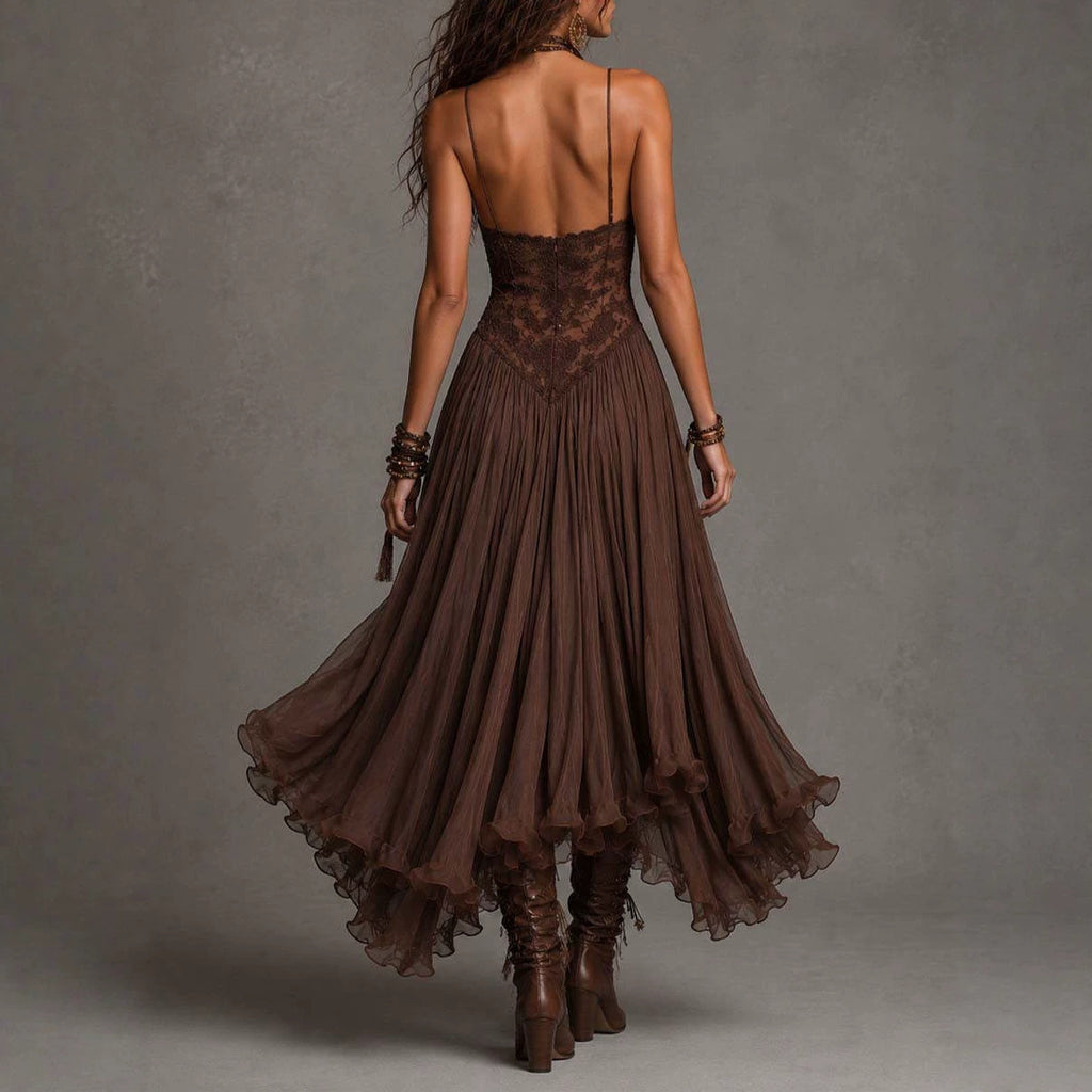A woman photographed from behind wearing a dark brown sleeveless maxi dress with a lace corset-style bodice and a flowing pleated skirt, paired with brown lace-up boots against a textured gray studio background.