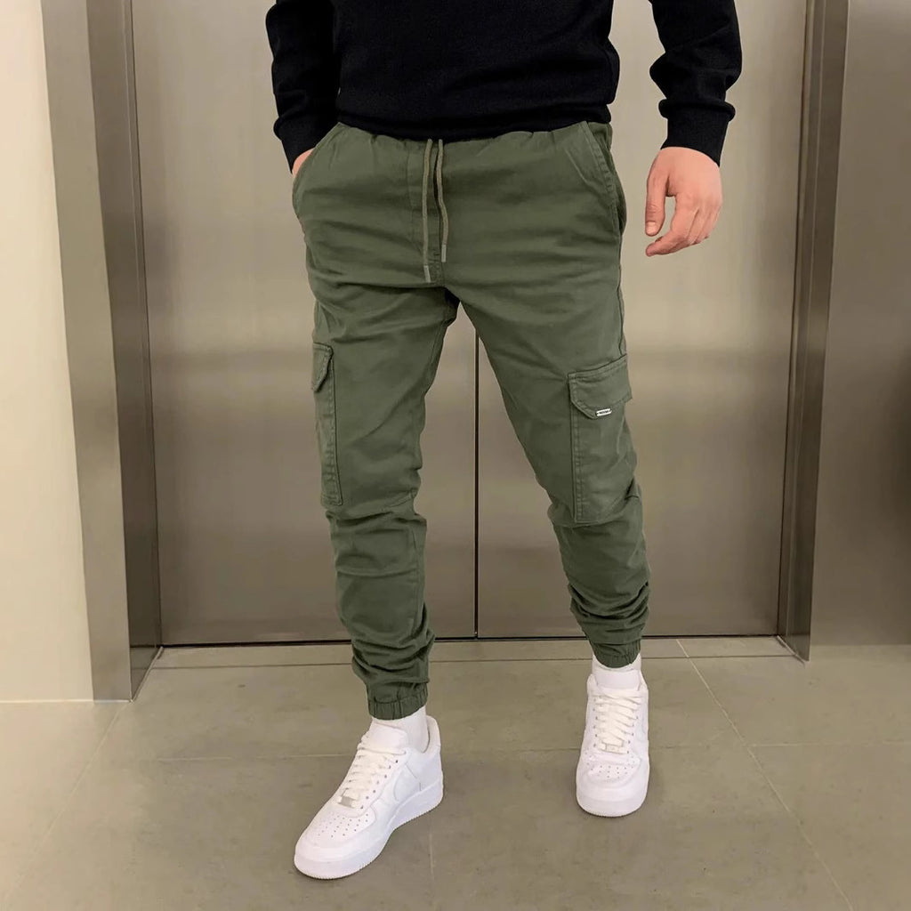 Person wearing green cargo jogger pants and white sneakers in an indoor setting.