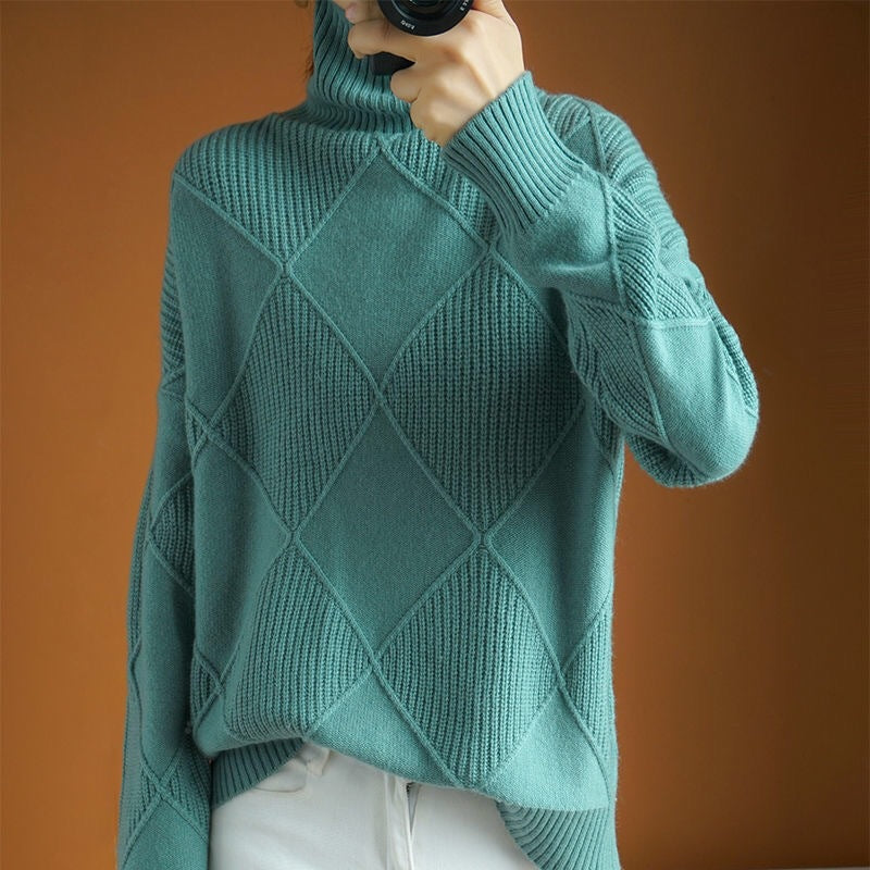Teal knitted sweater with diamond pattern worn by a person against an orange background
