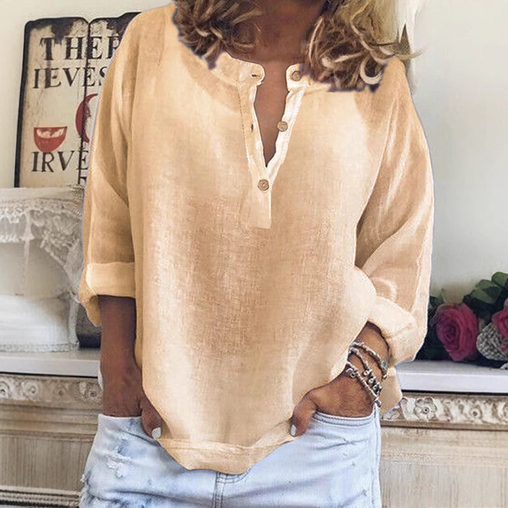 Person wearing a beige blouse with rolled-up sleeves and light blue jeans, standing indoors.