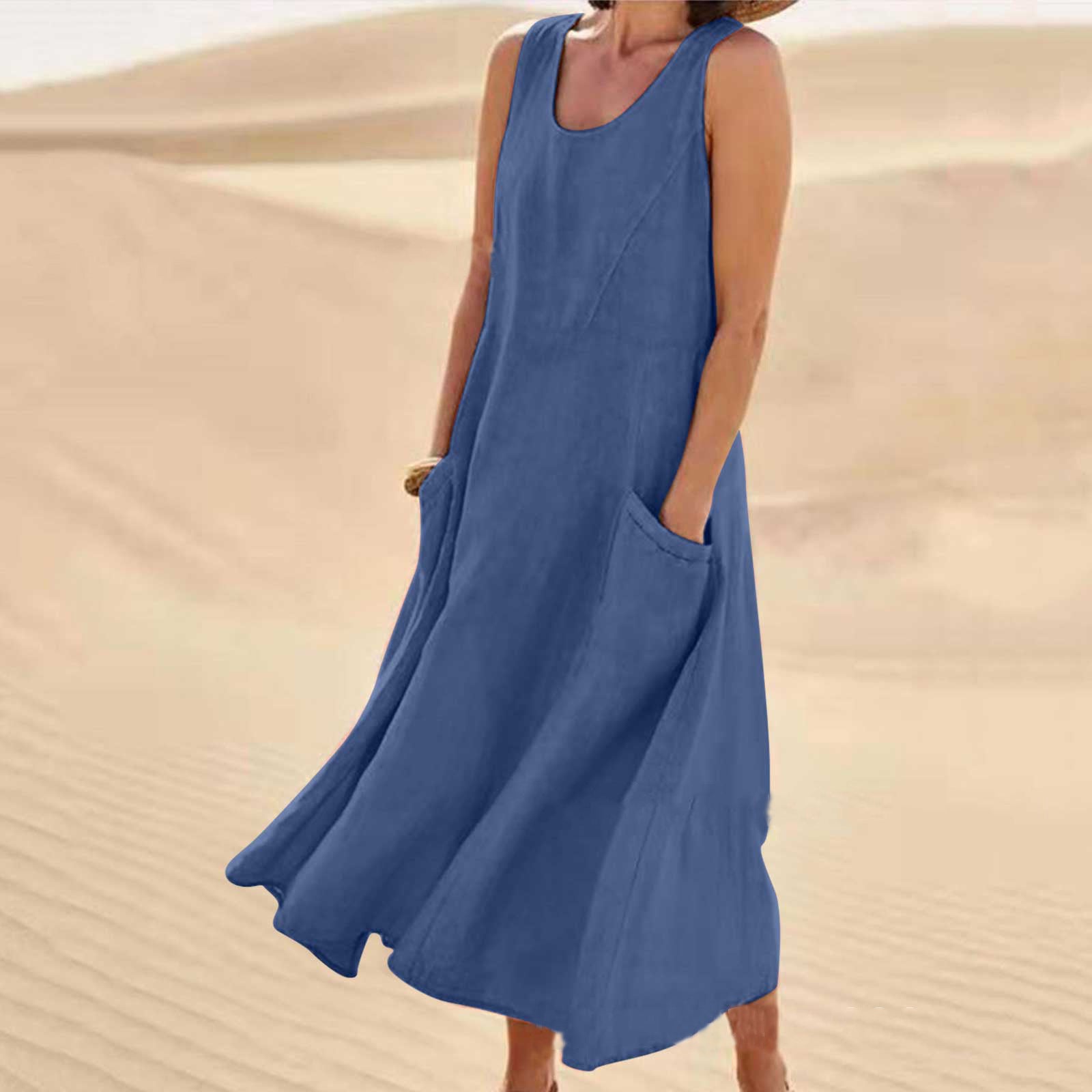 Person wearing a blue sleeveless dress with pockets against a sand dune background