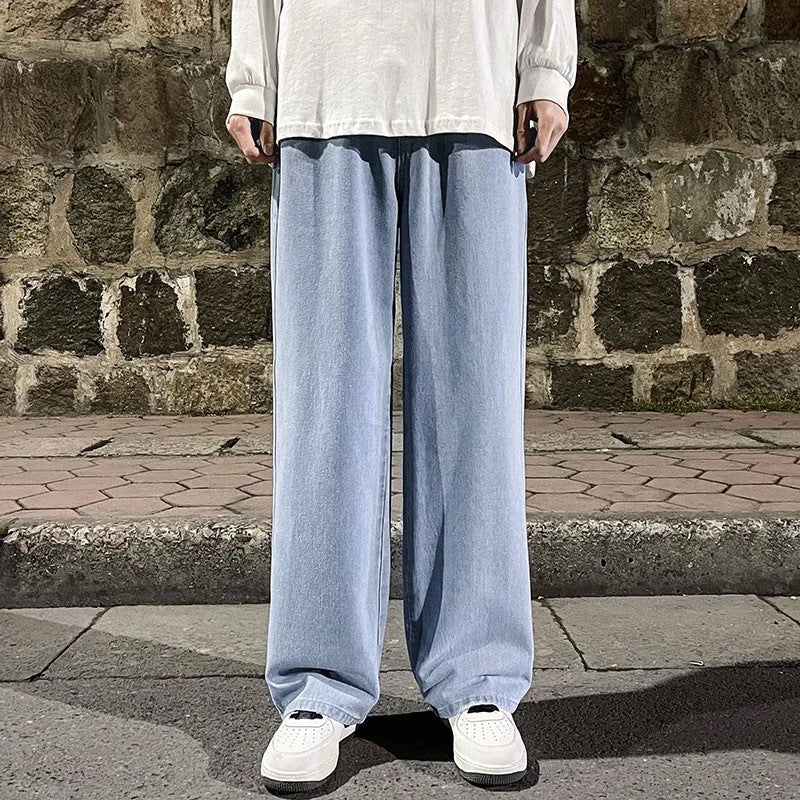Person wearing light blue pants and white shoes standing against a stone wall.