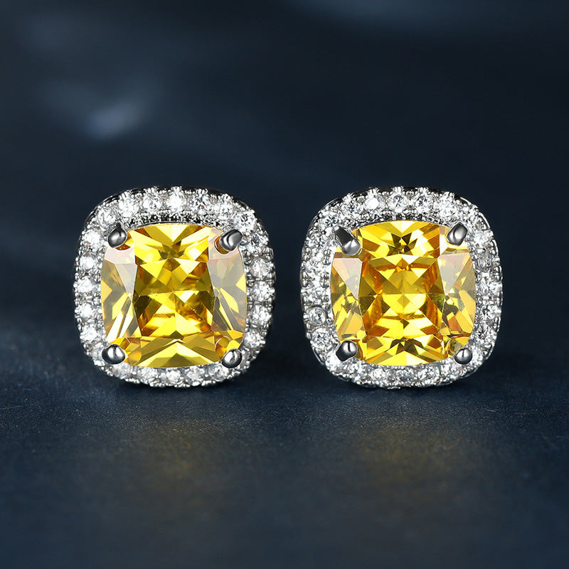 Pair of earrings with yellow gemstones and diamond-like stones on a dark background