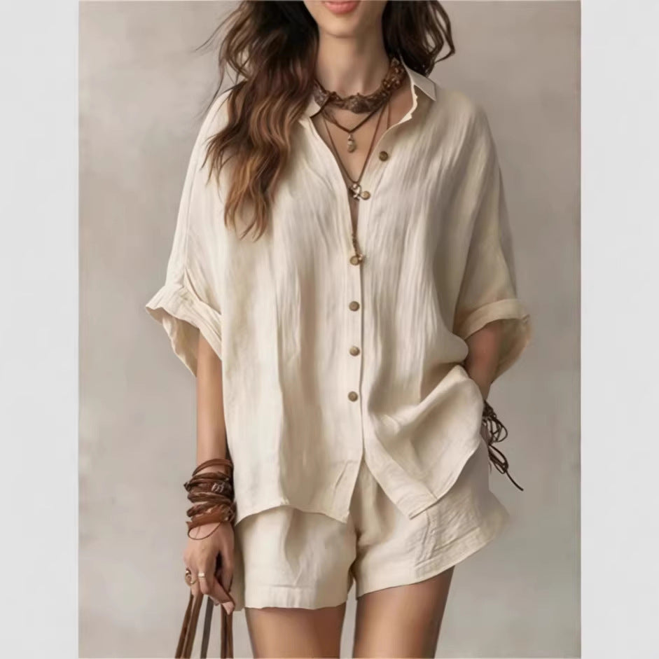 Woman wearing a beige outfit with layered necklaces and bracelets on a plain background