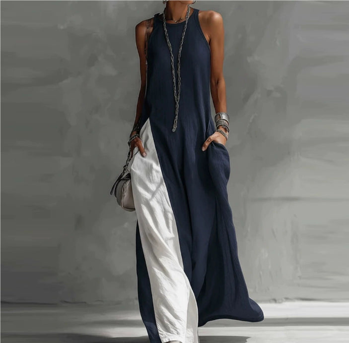 Person wearing a long navy dress with white pants against a gray background