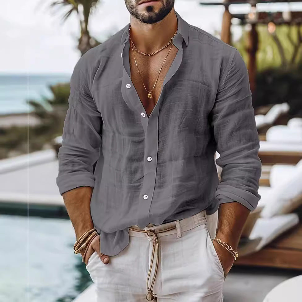 Man wearing a gray button-up shirt with rolled-up sleeves and light-colored pants by a poolside.