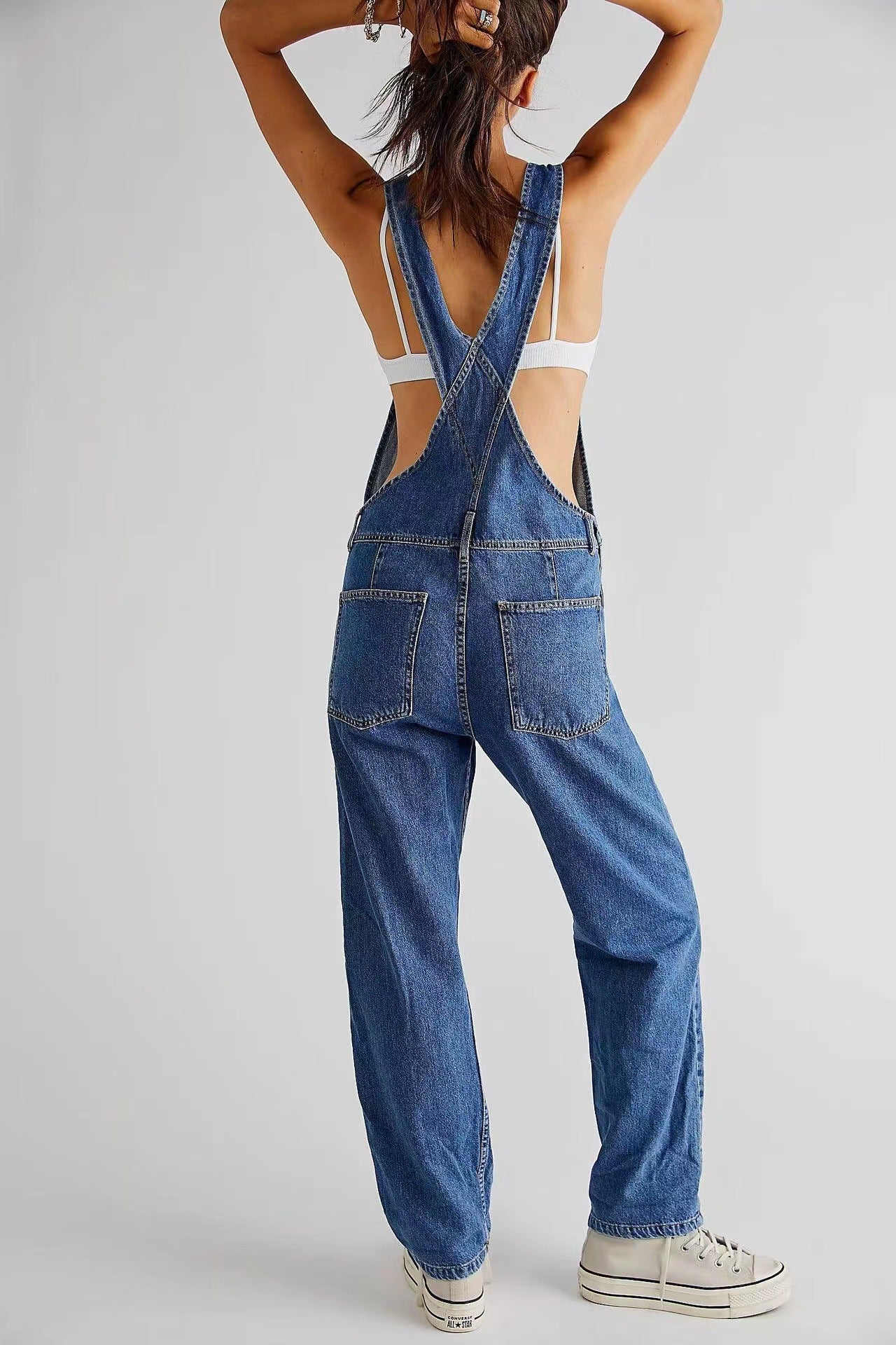 Person wearing blue denim overalls on a plain background
