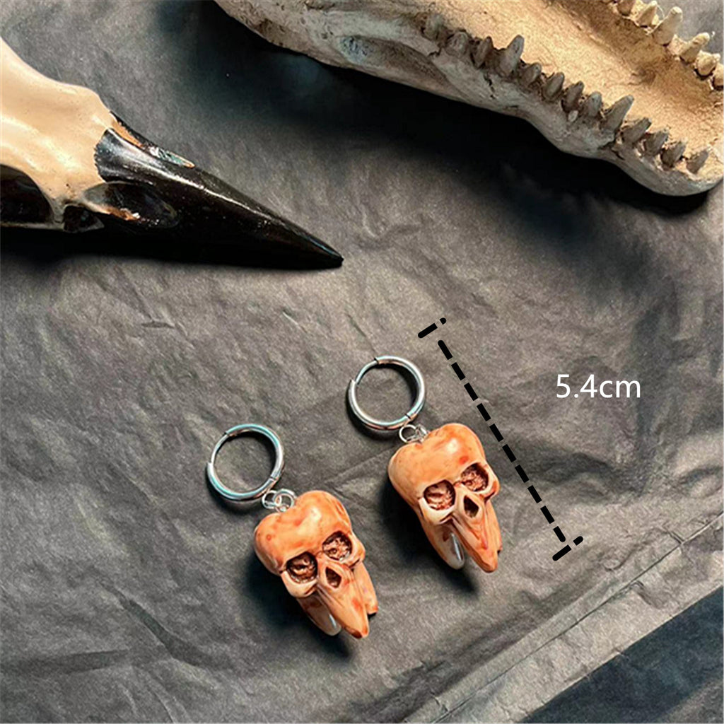 Two small skull-shaped charms on a dark surface with a measurement label.