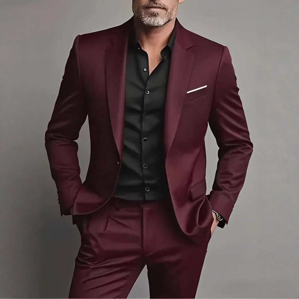 Man wearing a burgundy suit with a black shirt against a gray background