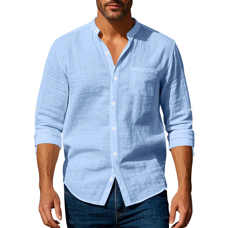 Man wearing a light blue button-up shirt with rolled-up sleeves on a white background