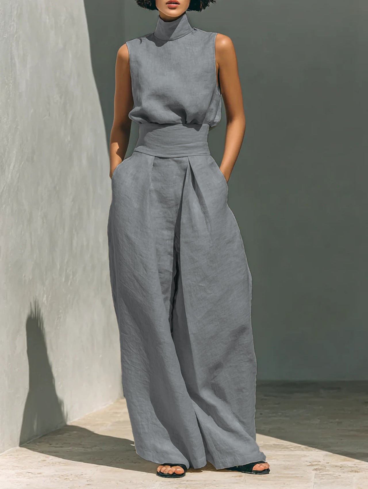 Person wearing a gray sleeveless top and wide-leg pants against a plain background