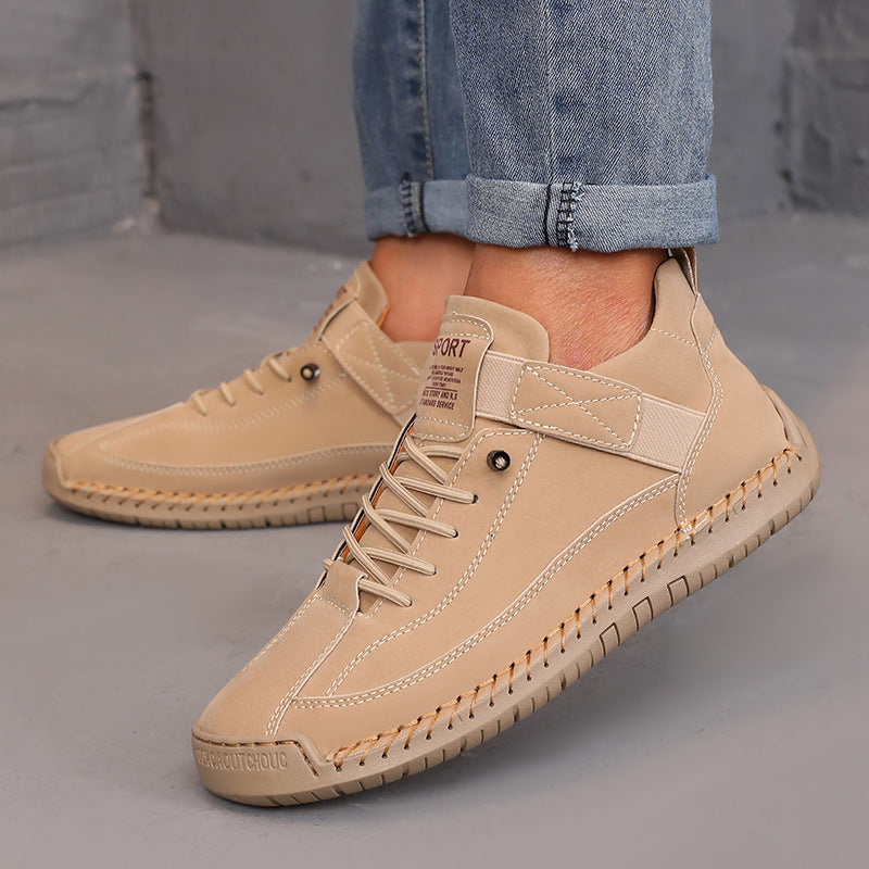 Beige leather shoes worn with rolled-up jeans on a gray surface.