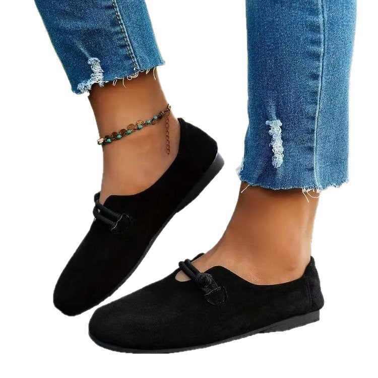 Black loafers worn with ripped jeans on a white background