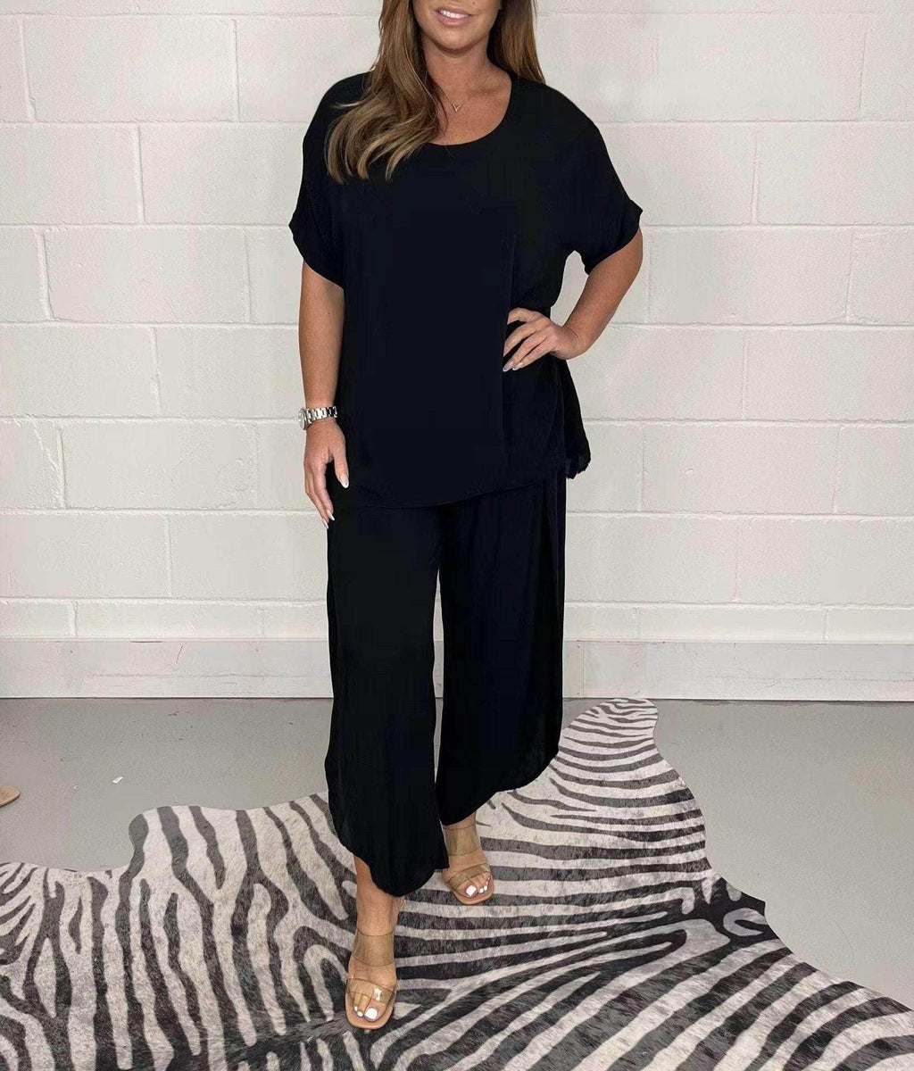 Woman wearing black loose-fit top and pants set from ZA-Zola, standing on zebra print rug