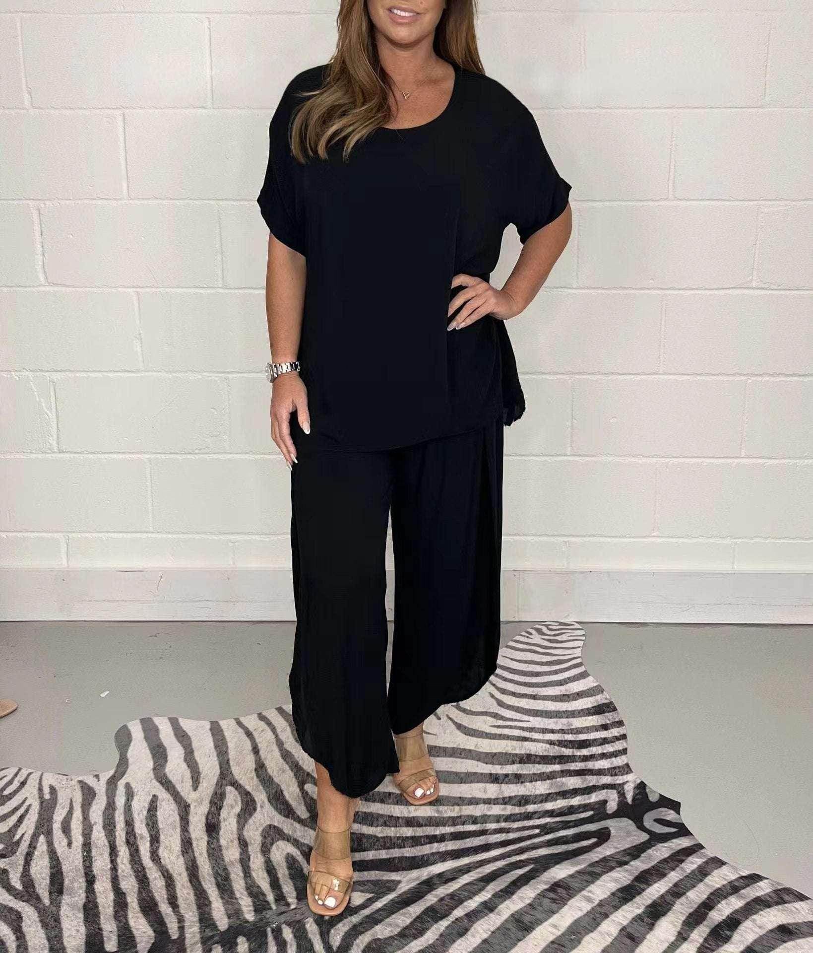 Woman wearing black loose-fit top and pants set from ZA-Zola, standing on zebra print rug