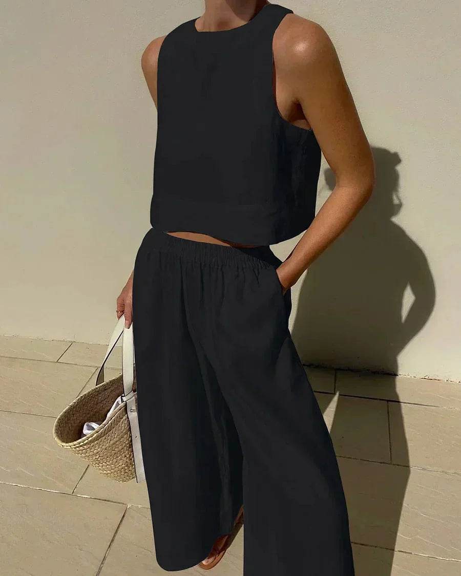 Woman modeling black sleeveless top and wide-leg pants from ZA-Zola, holding straw bag