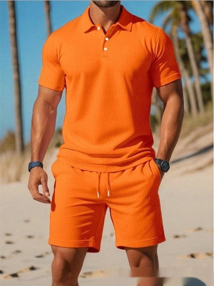 Person wearing an orange polo shirt and shorts set on a beach with palm trees in the background.