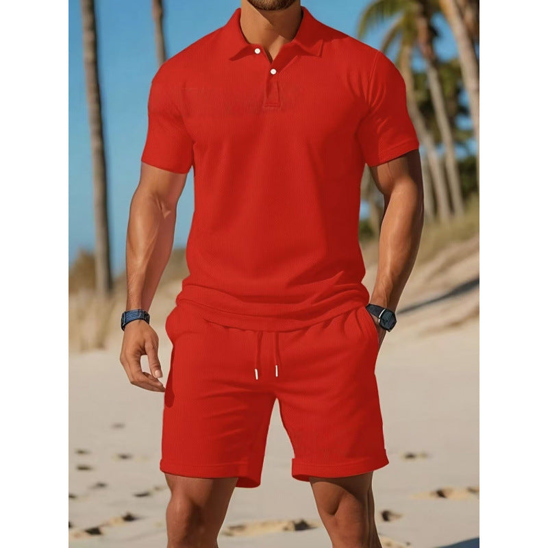 Man wearing a red polo shirt and shorts on a beach with palm trees in the background
