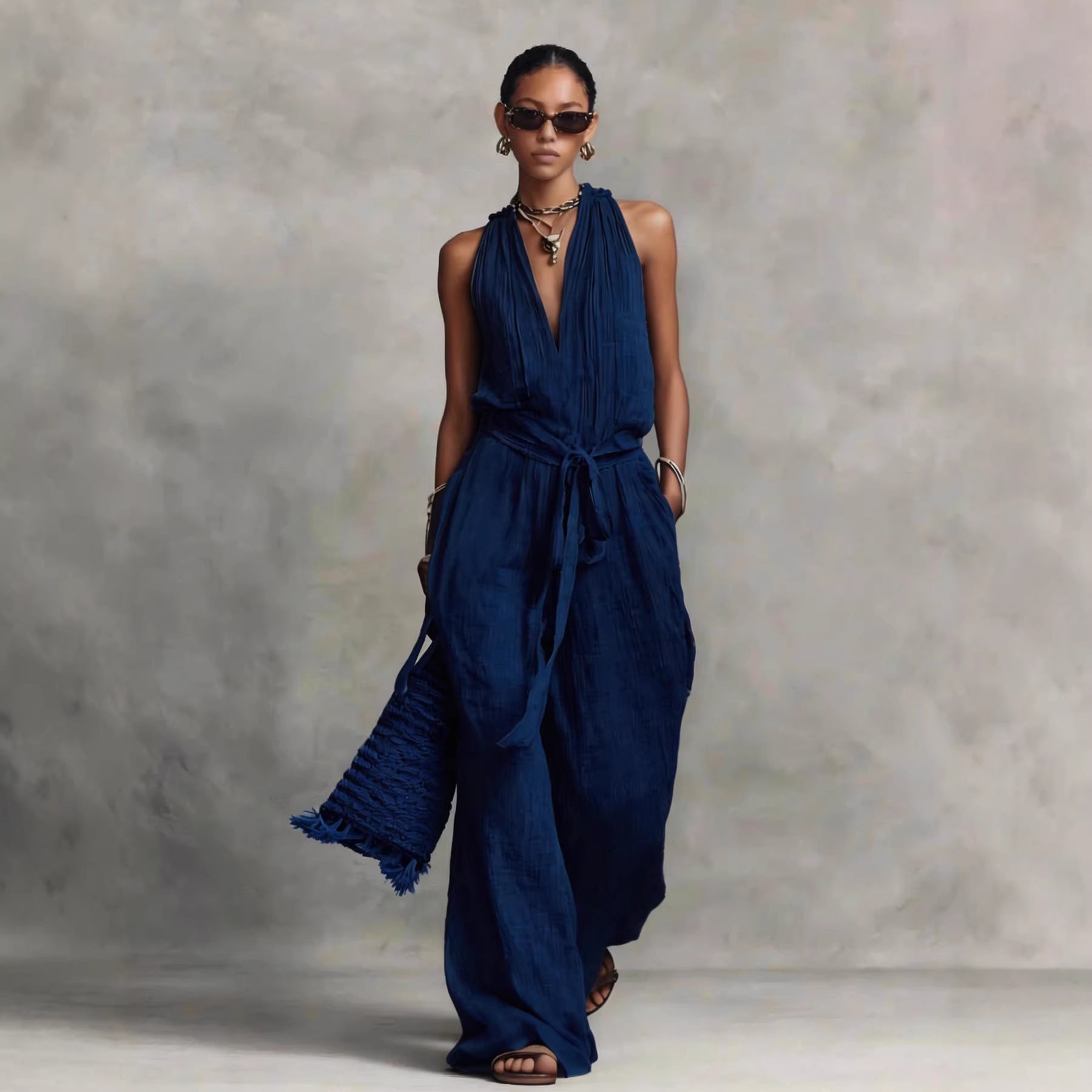 Woman wearing a long navy blue dress against a gray background