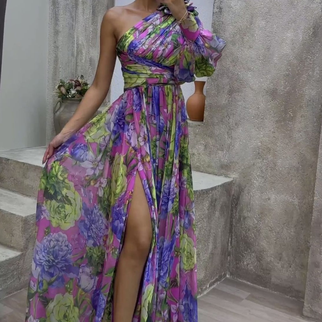 Woman wearing a colorful floral dress with a high slit, standing on stone steps.