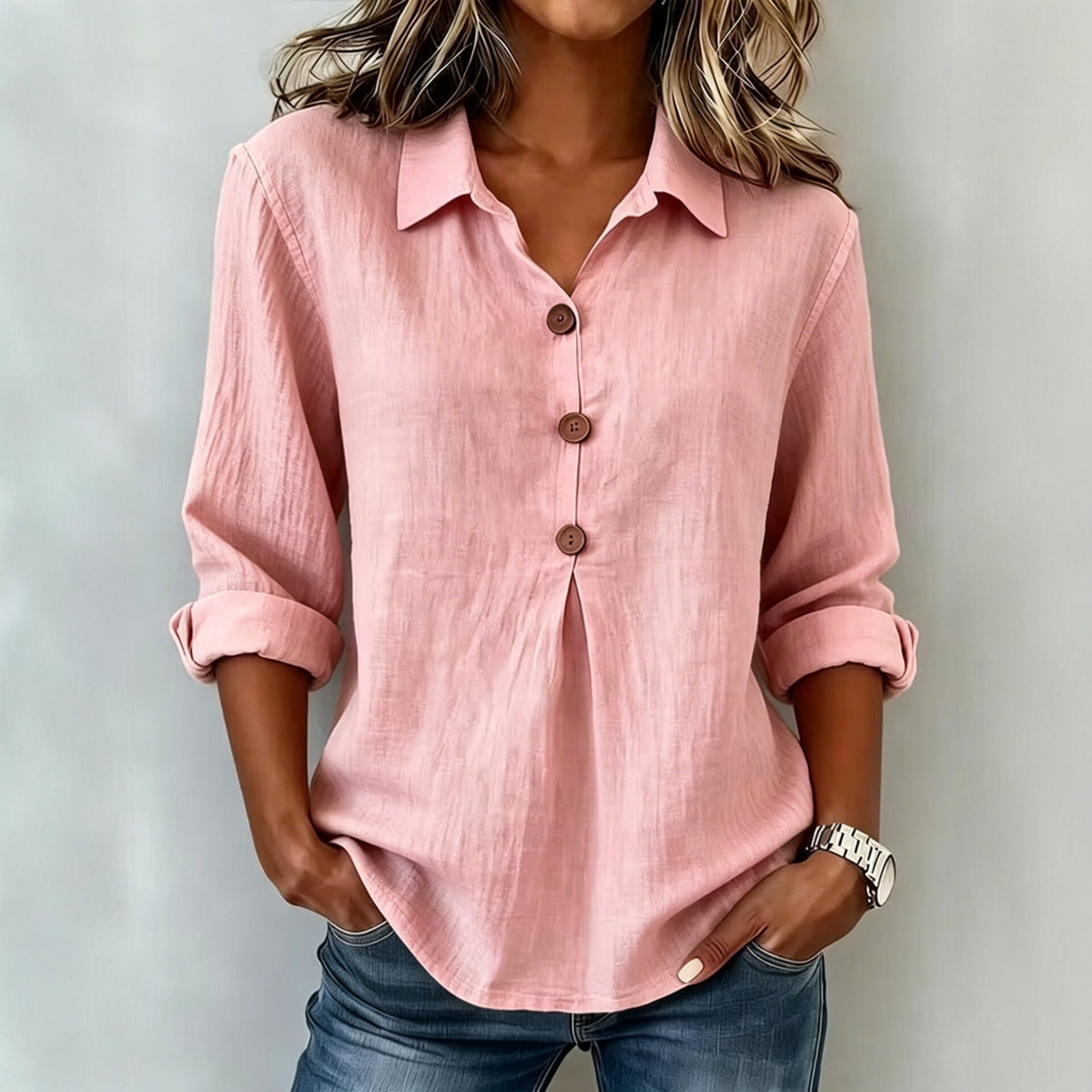 Person wearing a pink button-up shirt with rolled-up sleeves against a plain background