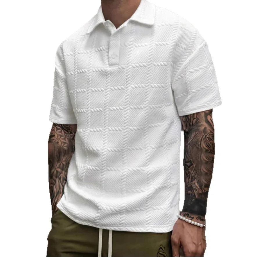 White patterned polo shirt worn by a person with tattoos on a white background