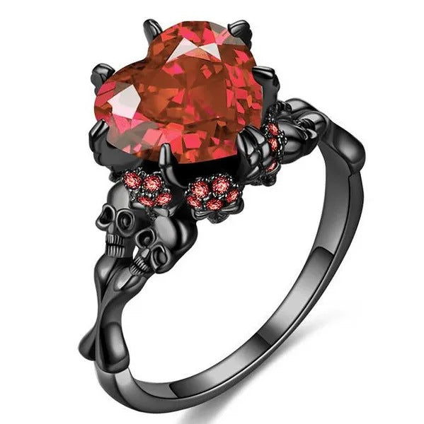 Black skull ring with a large red gemstone on a white background
