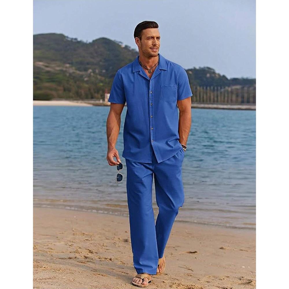 Man in a blue outfit walking on a beach with water and sky in the background