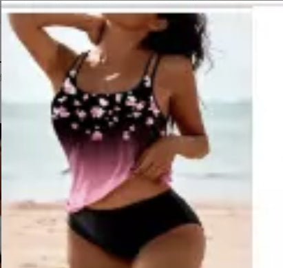 Woman in a black floral swimsuit with pink accents on a beach