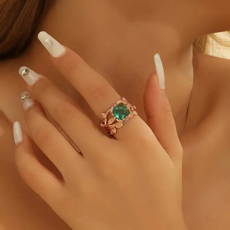 Close-up of a hand wearing a green gemstone ring with a blurred background