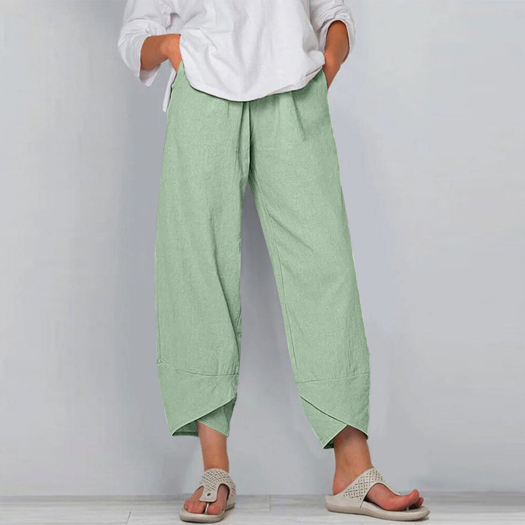 Person wearing light green wide-leg pants and a white shirt against a plain background
