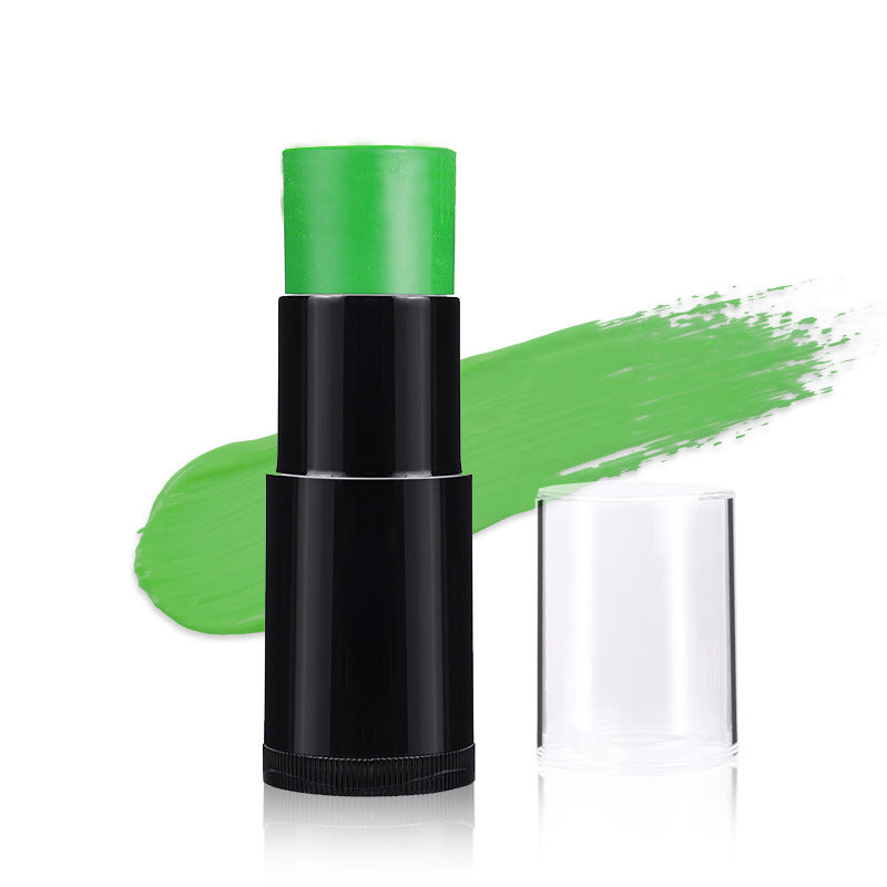 A green cosmetic stick product in a black tube with its clear cap removed, shown beside a bright green makeup smear on a white background.