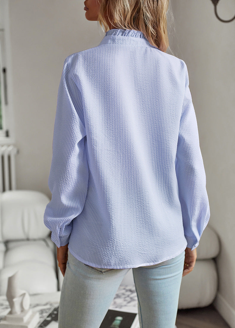 Person wearing a light blue textured shirt in a room with white furniture.