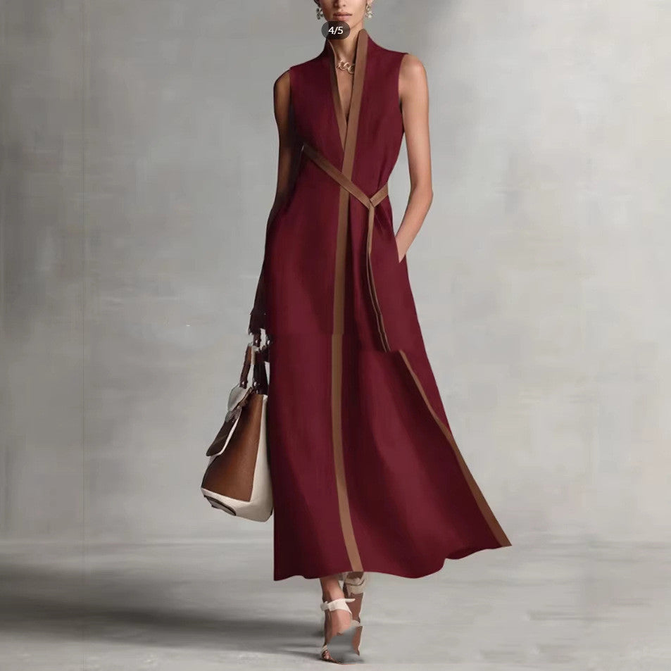 Woman wearing a burgundy dress with a brown belt against a gray background