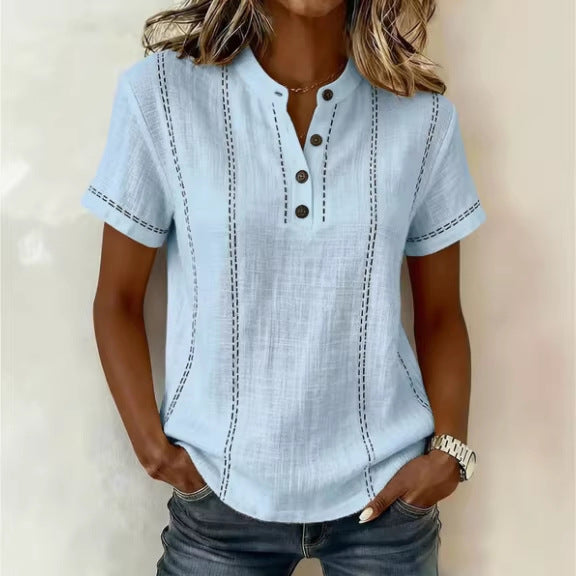 Light blue short-sleeve shirt with button details worn by a person against a neutral background