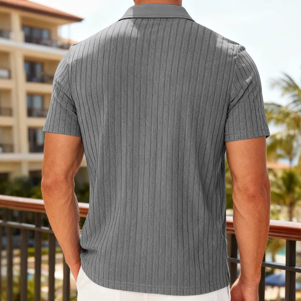 Person wearing a gray pinstripe shirt with a blurred background of a building and palm trees.
